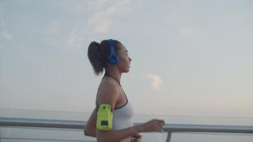 Female Runner in Headphones Jogging at Sunrise