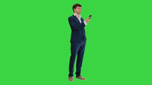 Serious Businessman Looking at His Phone on a Green Screen, Chroma Key.