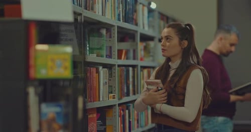 Pretty Girl Takes Books From the Shelf of the Rack Picks Up a Pile of Books
