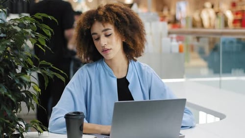 Focused Woman Works on Laptop in Modern Cafe