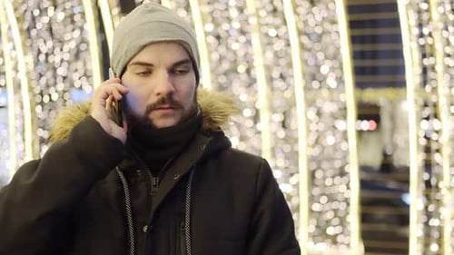 A man answers a phone call, rejoices, breaks into a smile. Have fun. Evening street lighting