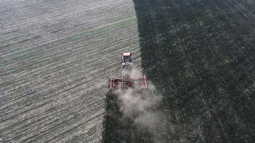 Aerial View of a Tractor Plows Field. View From the Drone. Camera Following the Tractor.