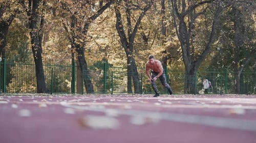 Muscular man is training on outdoor stadium.