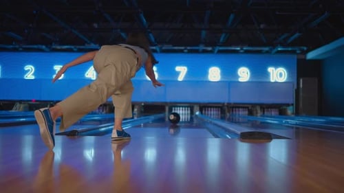 The Camera Follows One Woman Throwing a Bowling Ball on the Playing Track and Jumping Around