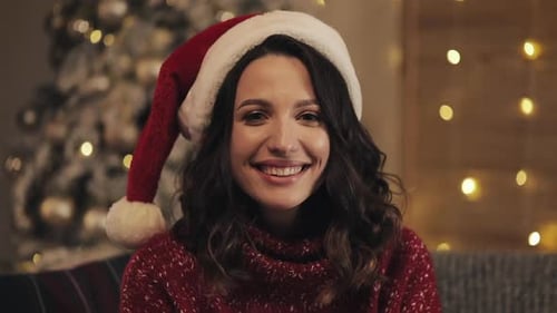 Smiling Woman Wearing Santa Hat with Christmas Tree