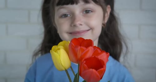 Smiling Girl Holds Spring Tulips at Home
