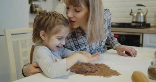 Child Spreads Dough with Mother in Kitchen