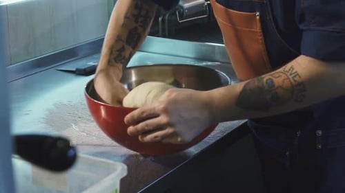 Chef Kneading Dough in Professional Kitchen