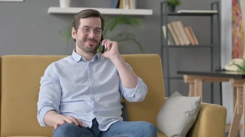 Man Talking on Phone on Yellow Couch