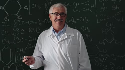Professor Writes Chemical Equations on Blackboard, Smiles