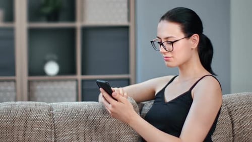 Woman Using Smartphone on Couch Indoors