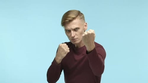 Stern Man Fists Threaten Posing in Front of Blue