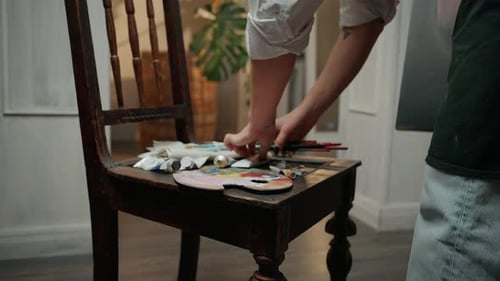 Nahaufnahme einer nicht wiederzuerkennenden Künstlerin, die Farbe aus der Tube auf der Palette drückt und zu malen beginnt