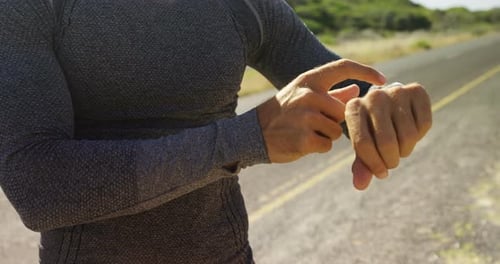 Man Checks Smart Watch on Rural Road