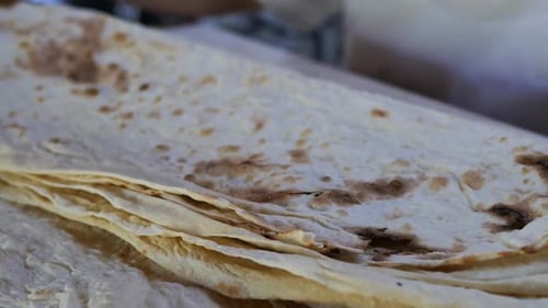 Des mains féminines prélèvent de nombreuses couches de pita traditionnel frais et les coupent au couteau