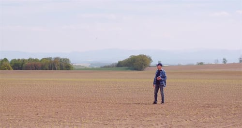 Farmer Examining Agricultural Field While Working on Digital Tablet Computer at Farm