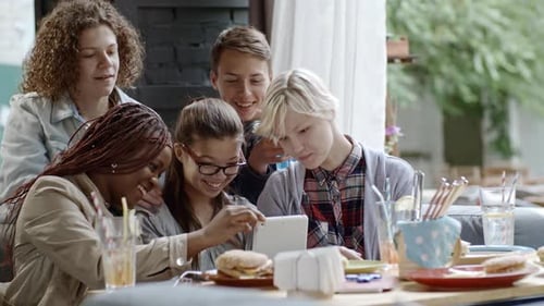 Company of Teenagers Using Digital Tablet in Outdoor Cafe