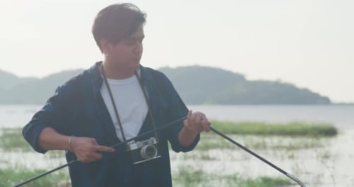 Man Preparing Fishing Rod by Tropical Lake