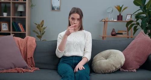 Woman demonstrating sign language while seated on couch