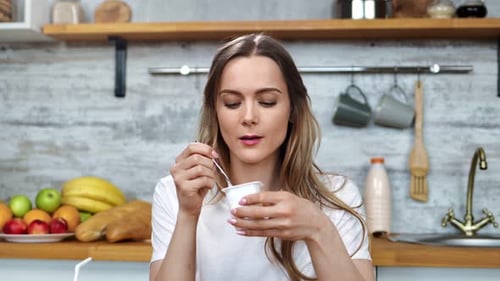 Woman Eating Yogurt in Bright Kitchen