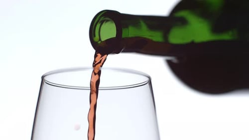 Pouring Red Wine into Glass From Green Bottle
