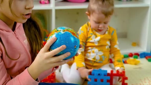 Child Showing Globe to Baby Inside Home