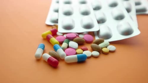 Close Up of Colorful Pills and Blister Pack on Orange Background