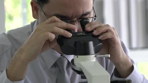 Scientist man is looking through microscope