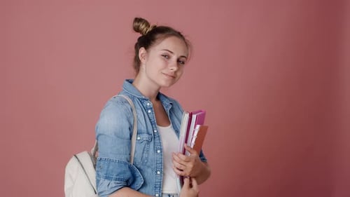 Smiling Young Woman Holding Books and Backpack