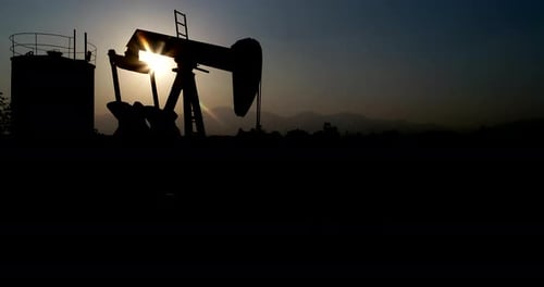 Industrial oil pump jack pumping crude oil for fossil fuel energy with drilling rig in oil field.