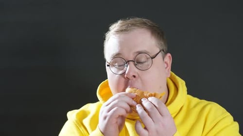 Man Enjoying a Burger Wearing Yellow Hoodie