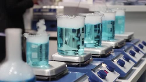Blue Liquid Stirring in Glass Beakers on Hotplates