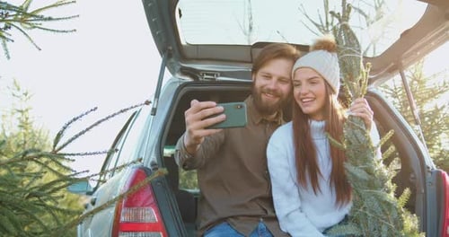 Cheerful Couple Taking Selfie with Christmas Tree