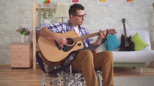 Young Adult Man Plays Guitar in Wheelchair