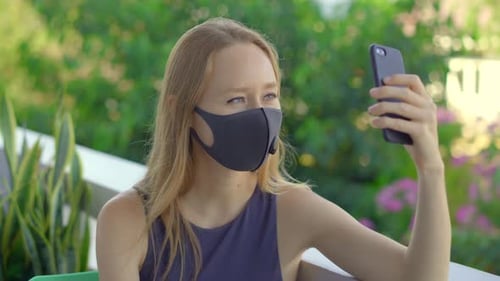 Woman with Mask Talking on Mobile Device Outdoors