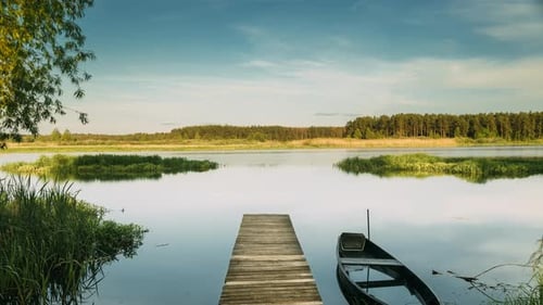 Lago o río de Bielorrusia y viejo barco de pesca de remo de madera cerca del antiguo muelle de madera en un hermoso verano