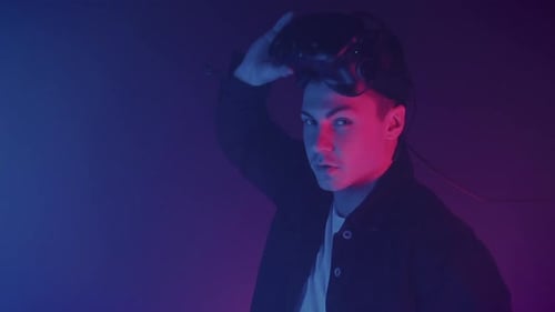 Young Adult Removes VR Headset in Neon Lighting
