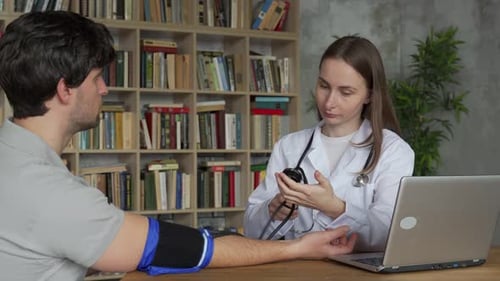 Woman Doctor Takes a Blood Pressure Measurement for a Male Patient at the Clinic