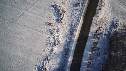 Luftaufnahme einer Asphaltstraße, umgeben von Schnee auf dem Land