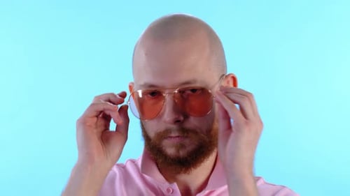 Bald Man Putting on Stylish Pink Aviator Sunglasses