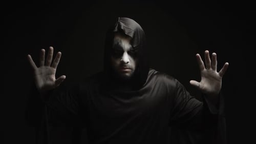 Dark Figure Raises Hands with Pale Painted Face