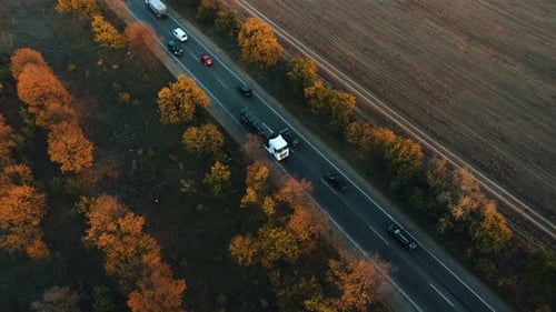 Aerial View of a Tanker Truck Driving in a Stream of Cars Along an Autumn Country Highway at Sunset