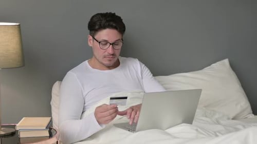 Man Uses Laptop and Credit Card in Bed