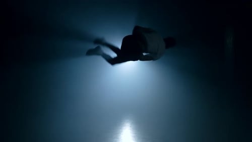 Young Man Practicing Parkour in Smoke Dark Studio. Silhouette of Urban Runner