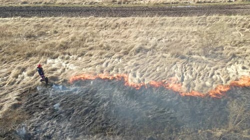 Aerial View of Firemen Extinguishing Grassland Field Burning with Red Fire During Dry Season