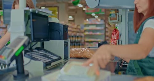 Female Cashier Punches Goods with a Scanner at the Supermarket Checkout