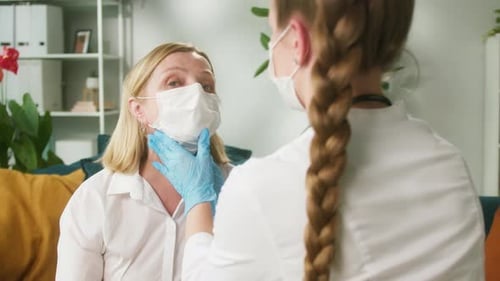 Doctor Examining Woman's Neck in Face Mask