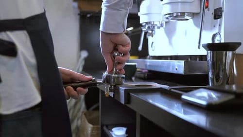 Male Barista Working with Ground Coffee While Standing in Kitchen of Cafe Spbas