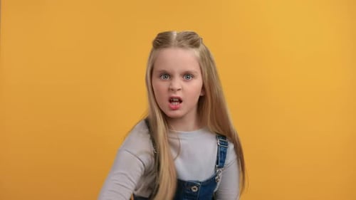 Portrait Aggressive Angry Female Kid Shouting Scolding with Negative Emotion Posing Isolated Orange
