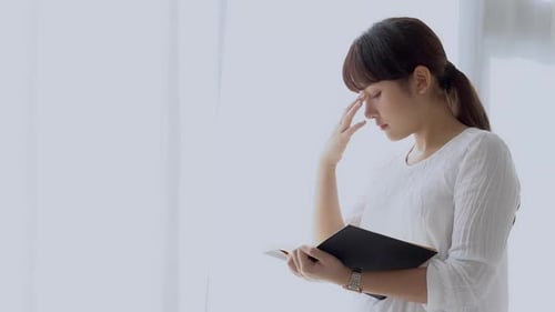 Woman Reading Book by Bright Window in Daytime
